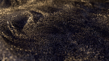 Black glitter with gold flecks. Golden loosened sand on ground.