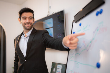 Businessman pointing on flip chart in office, focus on hand.