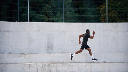 Side view. Sportive black man is running, morning routine