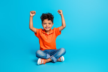 Full length photo of super winner young preschool boy fists up hooray yeah victory champion competition isolated on blue color background - obrazy, fototapety, plakaty