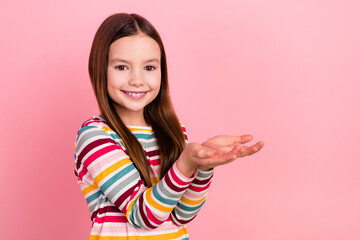 Photo of funny small girl holding two arms empty space advertising new games store advertise app store isolated on pink color background