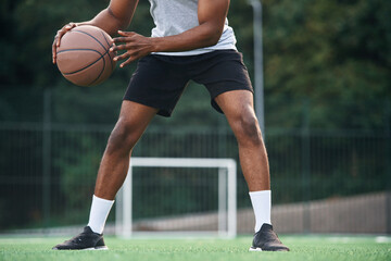Fototapeta premium Close up view. Young black man is with basketball ball outdoors