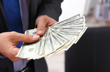 Man in suit and tie hold in arm pack of hundred dollar bills closeup. Stock market exchange earn...