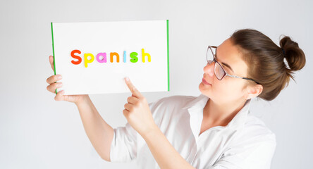 Learning Spanish educational courses. Native tutor, woman teacher in glasses with magnetic sign in hands. Study foreign language in online school. Speaking,reading,writing,linguistic knowledge skills