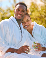Portrait Of Loving Couple Wearing Robes Outdoors With Drinks On Spa Day
