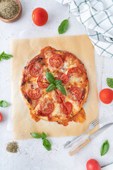 Pizza margherita with basil on a white background. Pizza with cheese and tomatoes cut into pieces. Homemade baking.