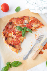 Pizza margherita with basil on a white background. Pizza with cheese and tomatoes cut into pieces. Homemade baking.