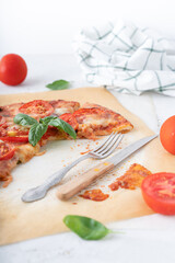 Pizza margherita with basil on a white background. Pizza with cheese and tomatoes cut into pieces. Homemade baking.