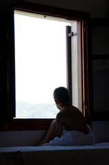 Little Boy on bed looking outside the window, on a Sunny morning near window.