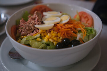 Delicious and fresh mixed salad with tuna, tomato, hard-boiled eggs, lettuce, sweet corn, grated carrot and black olives.