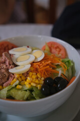Delicious and fresh mixed salad with tuna, tomato, hard-boiled eggs, lettuce, sweet corn, grated carrot and black olives.