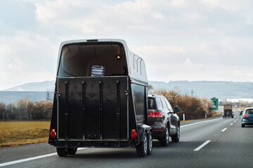 Car with a horse trailer on the road in Europe. Horse transport on the motorway.