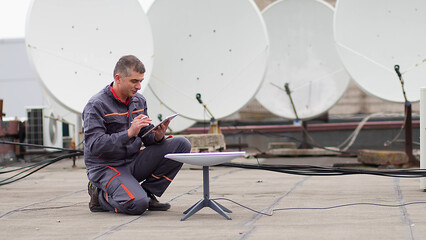 Operation and maintenance of satellite dishes under the sky, male engineer working on checking and maintaining satellite dishes. - obrazy, fototapety, plakaty