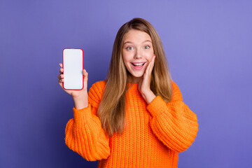 Photo of amazed young teen girl wear orange pullover promoting you scan qr code smartphone screen isolated on violet color background