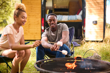 Close Up Of Couple Camping In Countryside With RV Toasting Marshmallows Outdoors On Fire