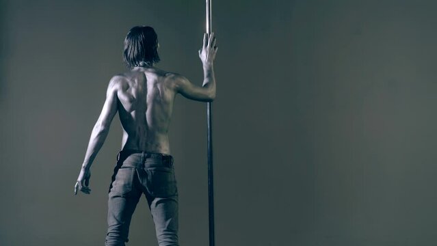 Pole dance. Sexy man dancing on pylon. Sexy slim and muscular male body. Flexible man gymnastic dancer man performing. Strong guy on pole dance. Shirtless gymnast exercising on pylon. Bare male torso.