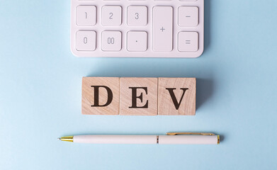 DEV on wooden cubes with pen and calculator, financial concept