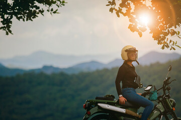 woman wearing safety helmet sitting on small enduro motorcycle against beautiful scenic of khao yai national park thailand