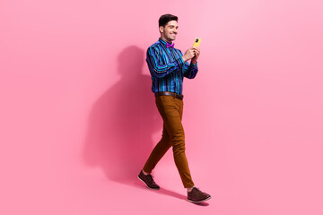 Full length photo of cheerful guy using apple iphone 15 when texting girlfriend invite her date at cafe isolated on pink color background