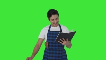 Happy Indian cook making food from recipe book Green screen