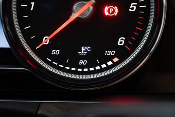 Modern car lit water or coolant temperature meter digital dial. Close up shot, rev meter above, no...