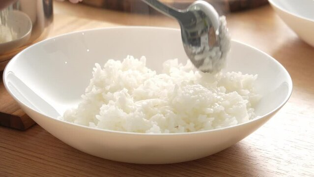 White rice is put on a plate. Serving hot steaming side dish. Cooked dinner. Food preparation. High quality 4k footage.