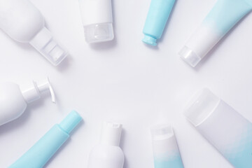 Bottles and tubes with cosmetic products on a soft blue background