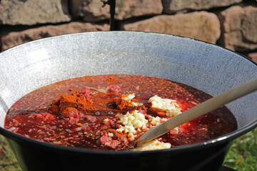 Meat and vegetables in a goulash kettle on a fire pit