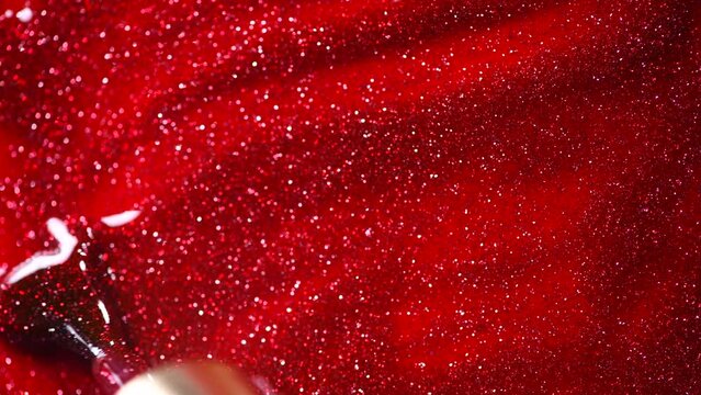 Red glitter nail polish UV gel background with brush. Nailpolish liquid surface, red shellac UV gel brush, varnish, manicure concept. Manicure salon, shellac texture background, backdrop. Top view