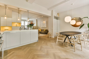 a kitchen and dining area in a modern apartment with white walls, wood flooring and light grey cabinetry
