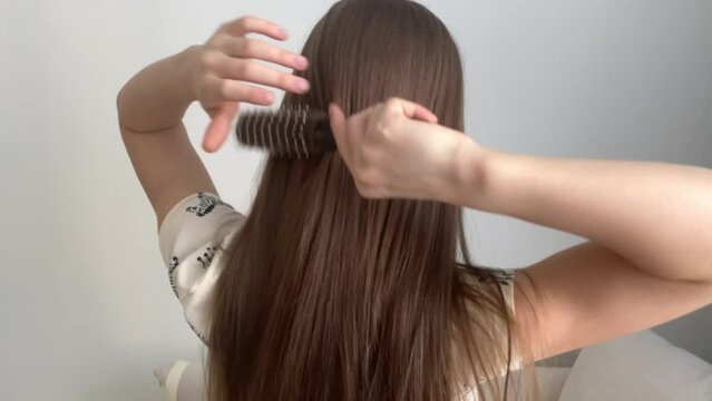 A child combs unruly long hair. Cute little girl playing with a hair comb