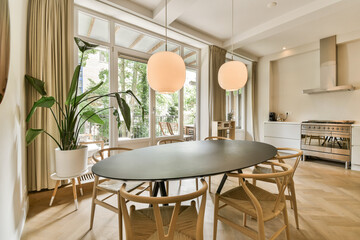 a dining room with wood flooring and large windows looking out onto the patio area, there is a round table surrounded by chairs