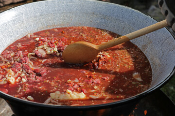 Meat and vegetables in a goulash kettle on a fire pit