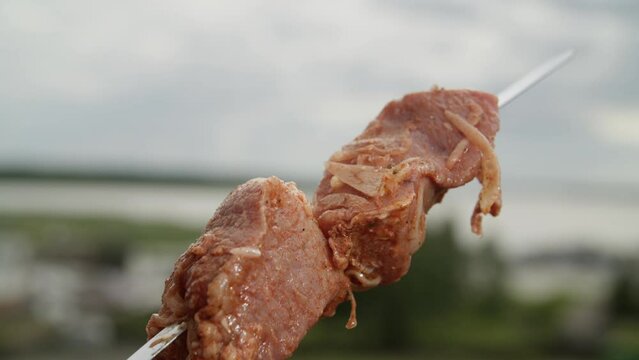 A man puts meat on skewers.