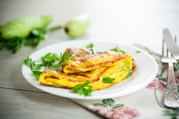 Fried omelet with zucchini, on a wooden table.