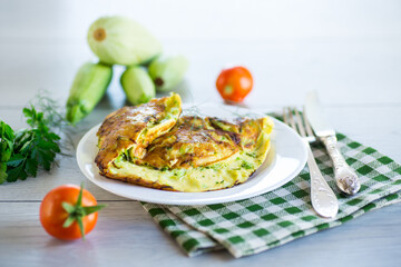 Fried omelet with zucchini, on a wooden table.