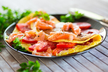 Fried omelette with tomatoes, vegetables and pieces of lightly salted red fish.