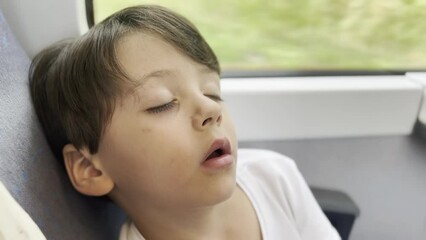 Young Boy Takes a Deep Nap During a Daytime Train Journey, Sleeping with Mouth Open and Appearing to Be Dreaming and Talking