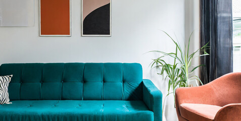 teal sofa and terra cotta armchair against white wall with art posters scandinavian style ho 