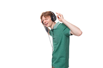 young positive slender student european man with red hair listens to music in headphones with a wire