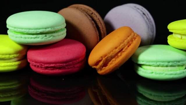 Lots of colorful macaroons on black background with reflection. Traditional french dessert