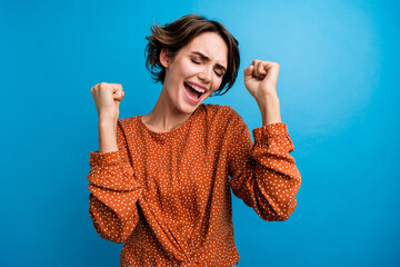 Photo of excited lady raise hands fists completed hard level mobile app game isolated blue color background