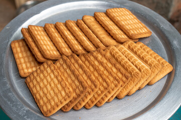 Brown Wheat biscuits in the steel plate with blury background. Tea Biscuit morning breakfast