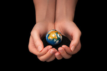 Woman’s hands holding planet Earth on black background