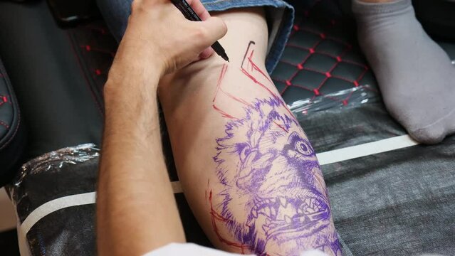 Making a tattoo based on a sketch drawn on the leg.