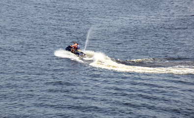 Two men jumps on the  water scooter above the water. Men speeding on powerboat on lake during summer vacation