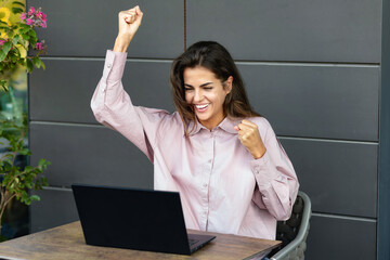 Businesswoman working remotely outside the office, sitting in a cafe is satisfied with the results...