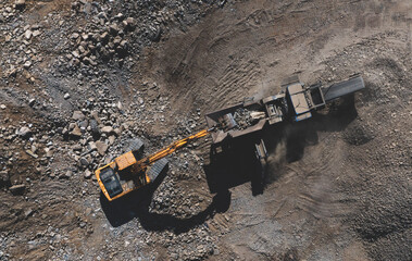 Excavator loading old concrete into stone jaw crusher. Stone crushing machine on landfill....