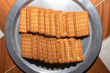 Brown Wheat biscuits in the steel plate with blury background. Tea Biscuit morning breakfast