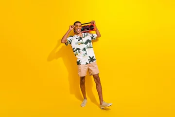  Full size photo of handsome young guy dancing tape recorder discotheque wear trendy palms print outfit isolated on yellow color background © deagreez